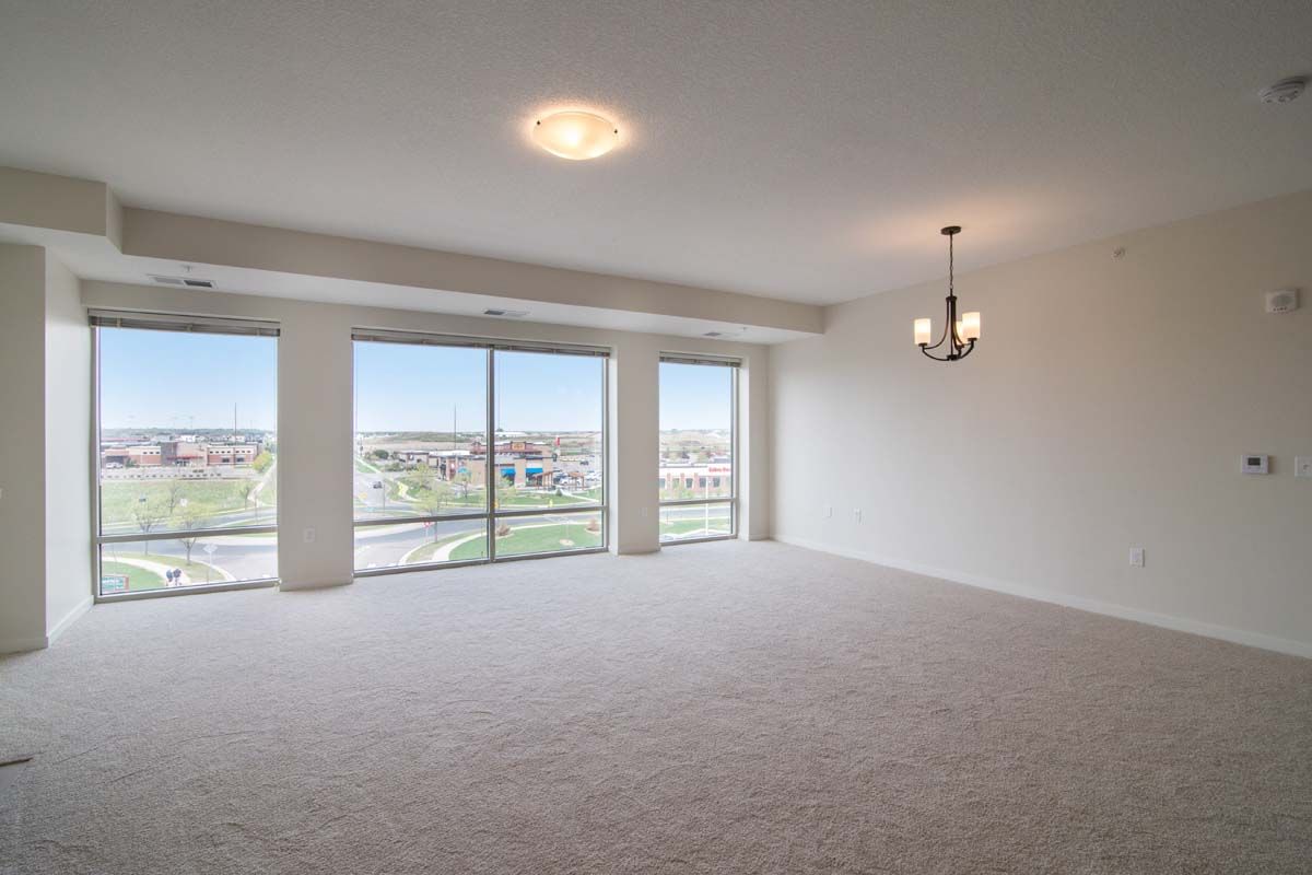 A spacious, empty room with large windows and a chandelier.