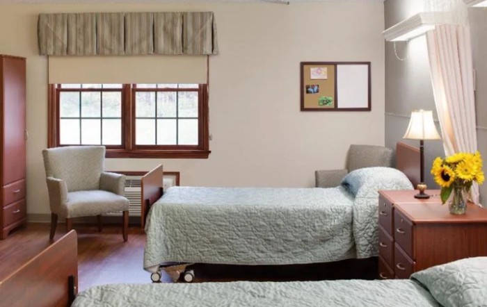 A neatly arranged hospital room with twin beds and comfortable seating.