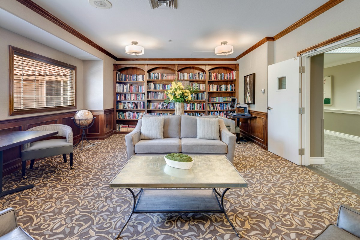 A cozy living room with a sofa, coffee table, and bookshelves lining the walls.