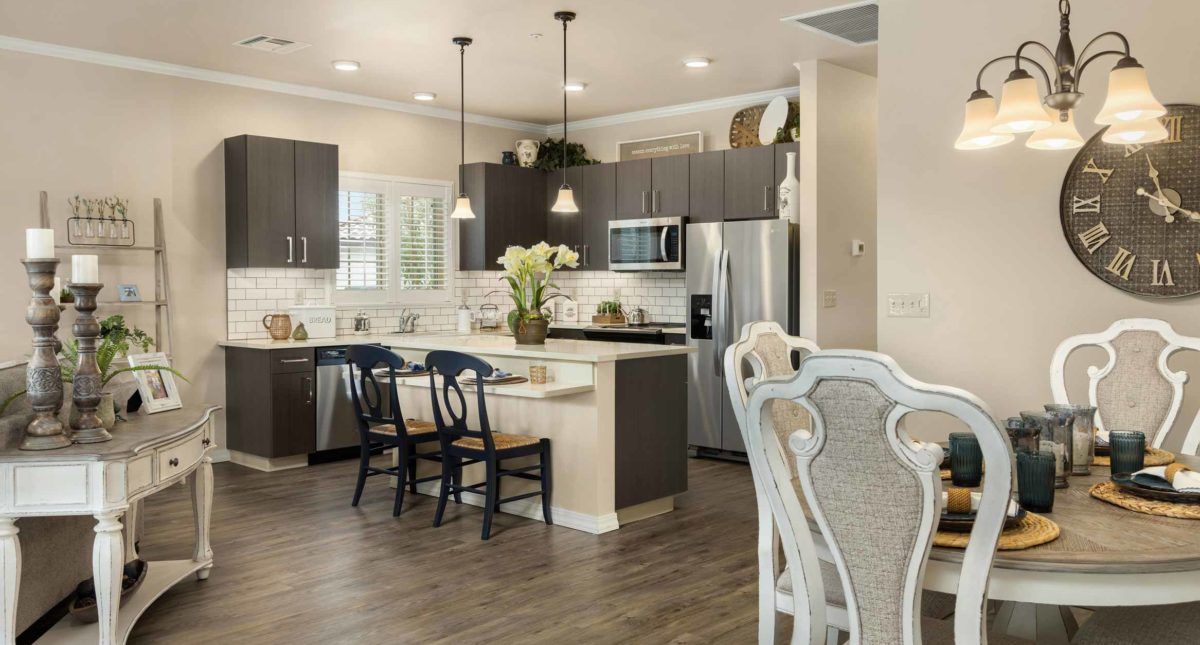 A modern kitchen with dark cabinetry, a central island, and stainless steel appliances.