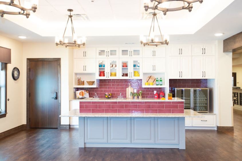 A modern kitchen with a central island, white cabinets, and colorful tile backsplash.