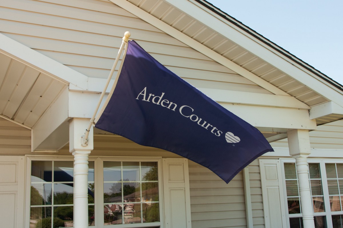 A flag with 'Arden Courts' text displayed outside a building.