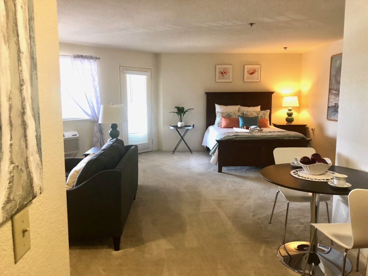 Cozy studio apartment with a comfortable bed, sofa, and dining area.