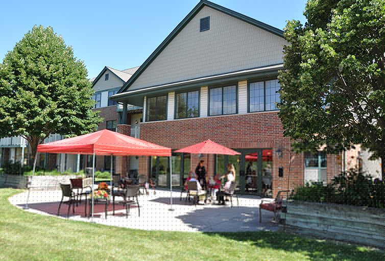People enjoying a sunny day on a patio with red umbrellas.
