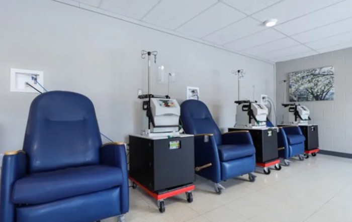 A row of dialysis machines with comfortable chairs in a healthcare facility.