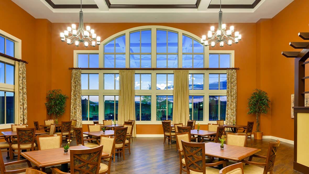 A spacious dining area featuring large arched windows and elegant chandeliers.