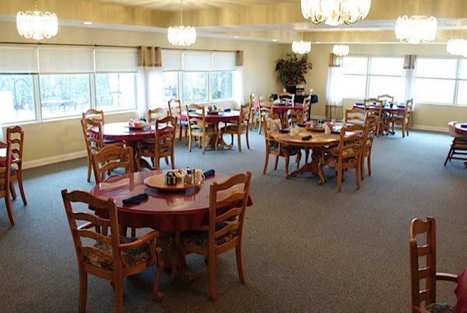 A well-lit dining area with multiple round tables and chairs.