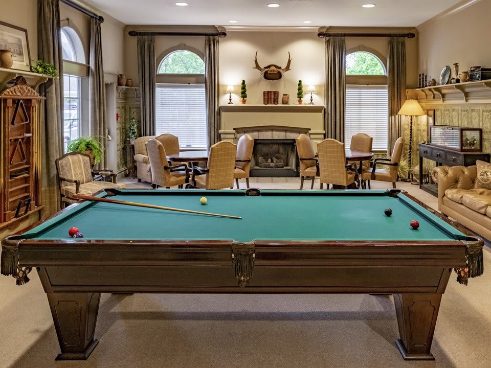 A cozy game room featuring a billiard table and seating area by the fireplace.