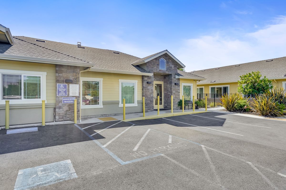 A small commercial building with a parking lot and entrance, captured during the daytime.