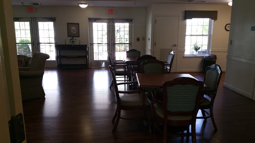A well-furnished room with tables and chairs, illuminated by natural light from the windows.