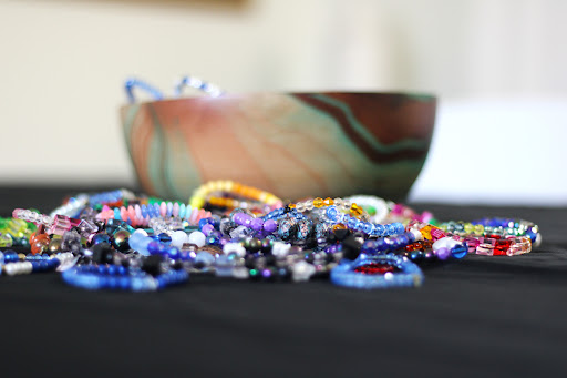 A vibrant assortment of beads scattered on a surface, with a beautifully patterned bowl in the background.