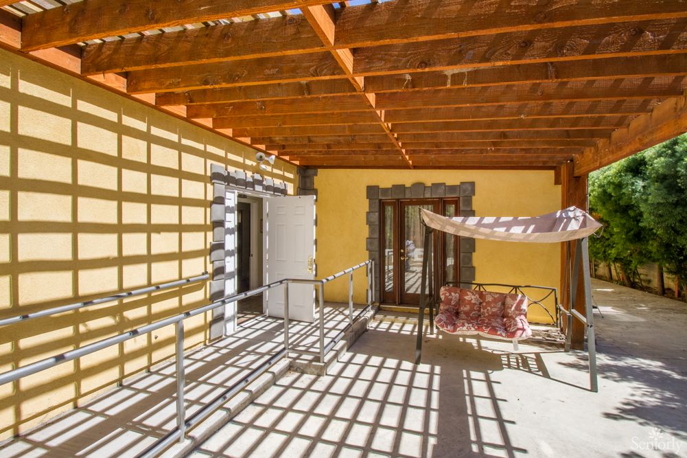 A sunlit patio with a wooden pergola casting intricate shadows.