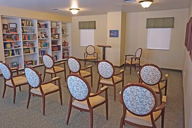 A small room with chairs arranged in rows, a podium, and bookshelves along the wall.