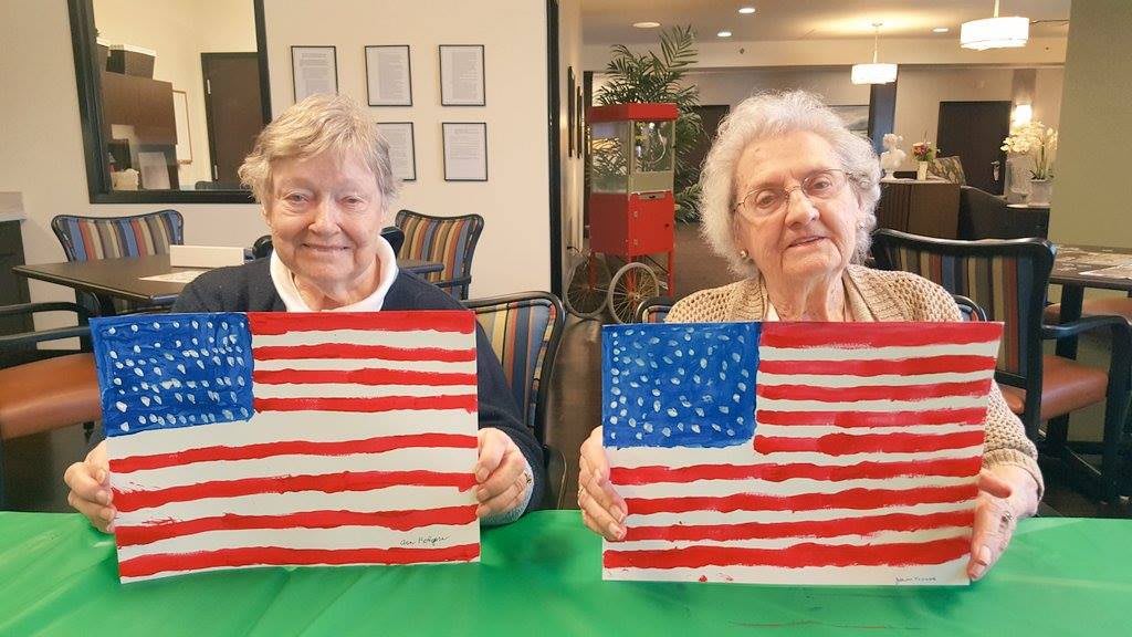 Two seniors proudly display their American flag paintings.