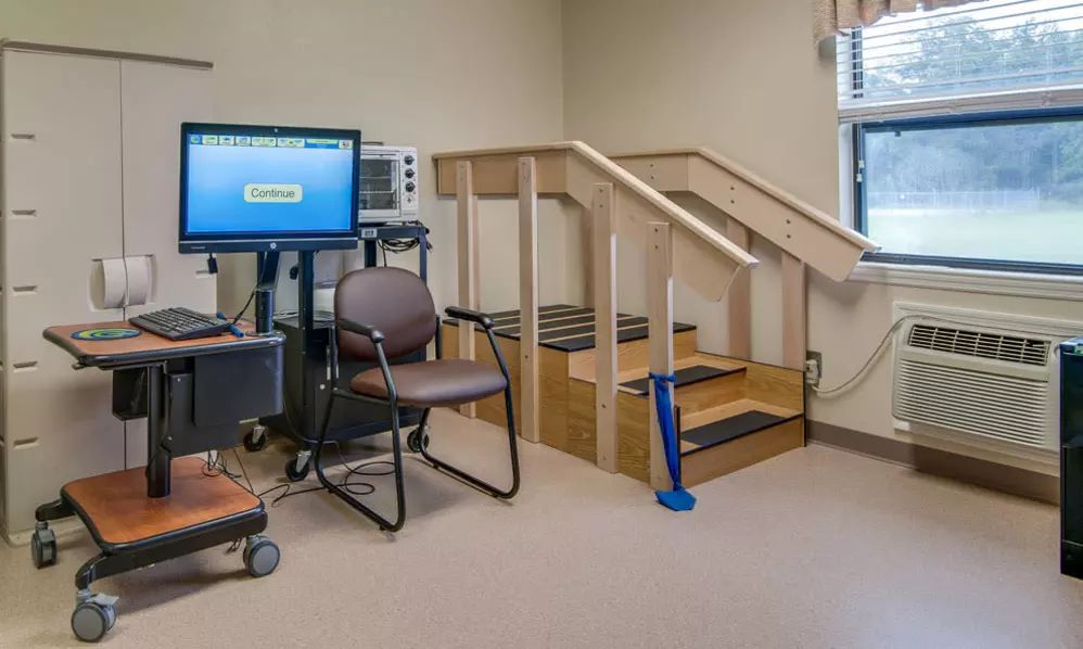 A physical therapy room featuring exercise equipment and a small staircase for rehabilitation exercises.