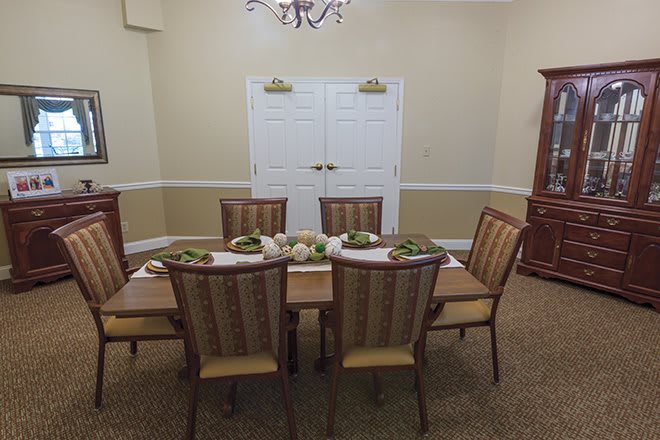 A well-decorated dining room with a table set for a meal and elegant chairs around it.