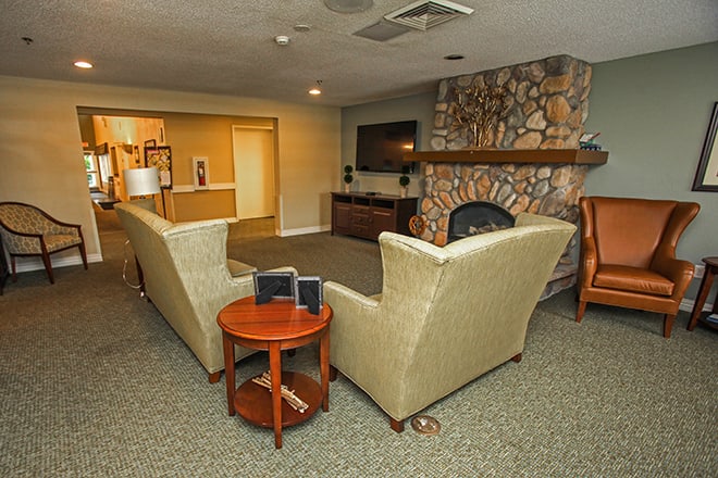 A cozy living room featuring sofas arranged around a fireplace and a television.