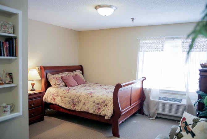 A cozy bedroom with a wooden sleigh bed, floral bedding, and a soft carpeted floor.