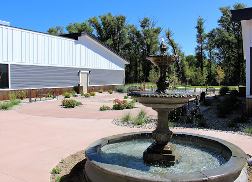 A serene garden featuring a decorative fountain and a landscaped area, set against a clear blue sky.