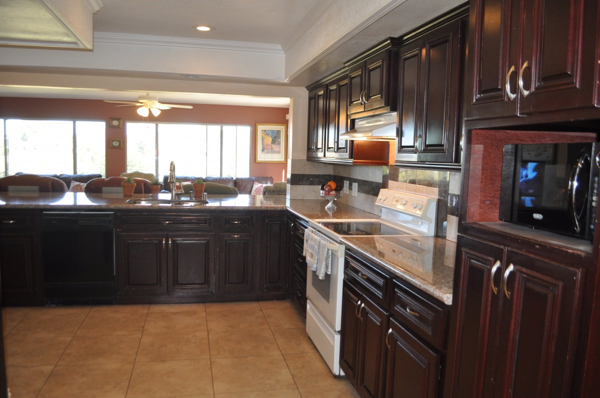 A spacious kitchen with dark cabinets and modern appliances.