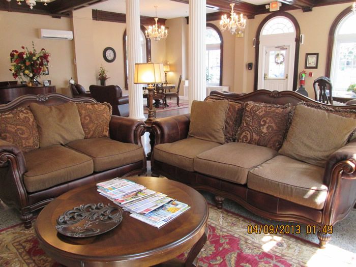 A luxurious living room featuring elegant sofas, a round coffee table, chandeliers, and decorative pillars.