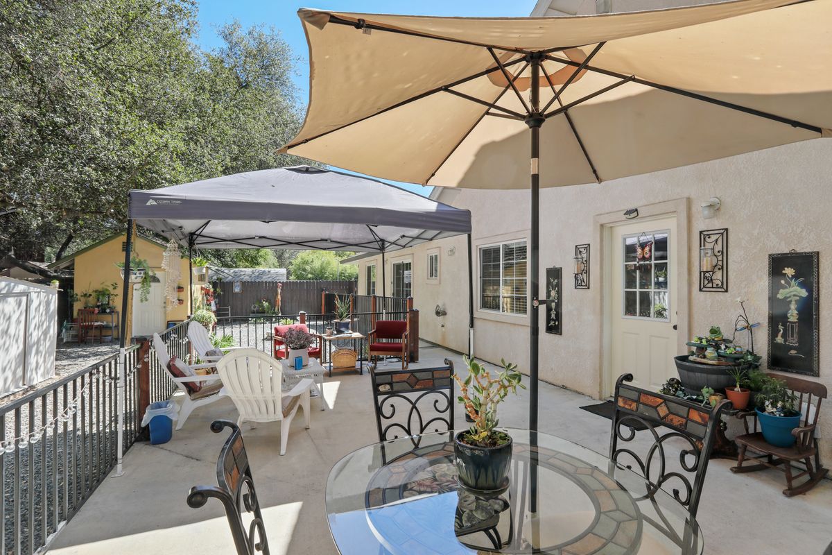A sunny backyard patio with umbrellas and outdoor furniture.