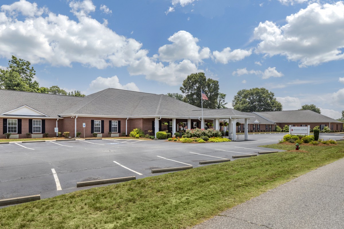A suburban office building with an adjacent parking lot under a partly cloudy sky.
