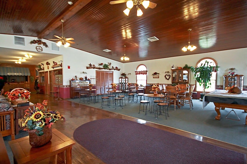 Spacious restaurant dining area with wooden floors, ceiling fans, and decorative elements.