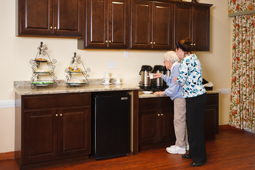 A caregiver assists an elderly individual in a modern kitchen setting.