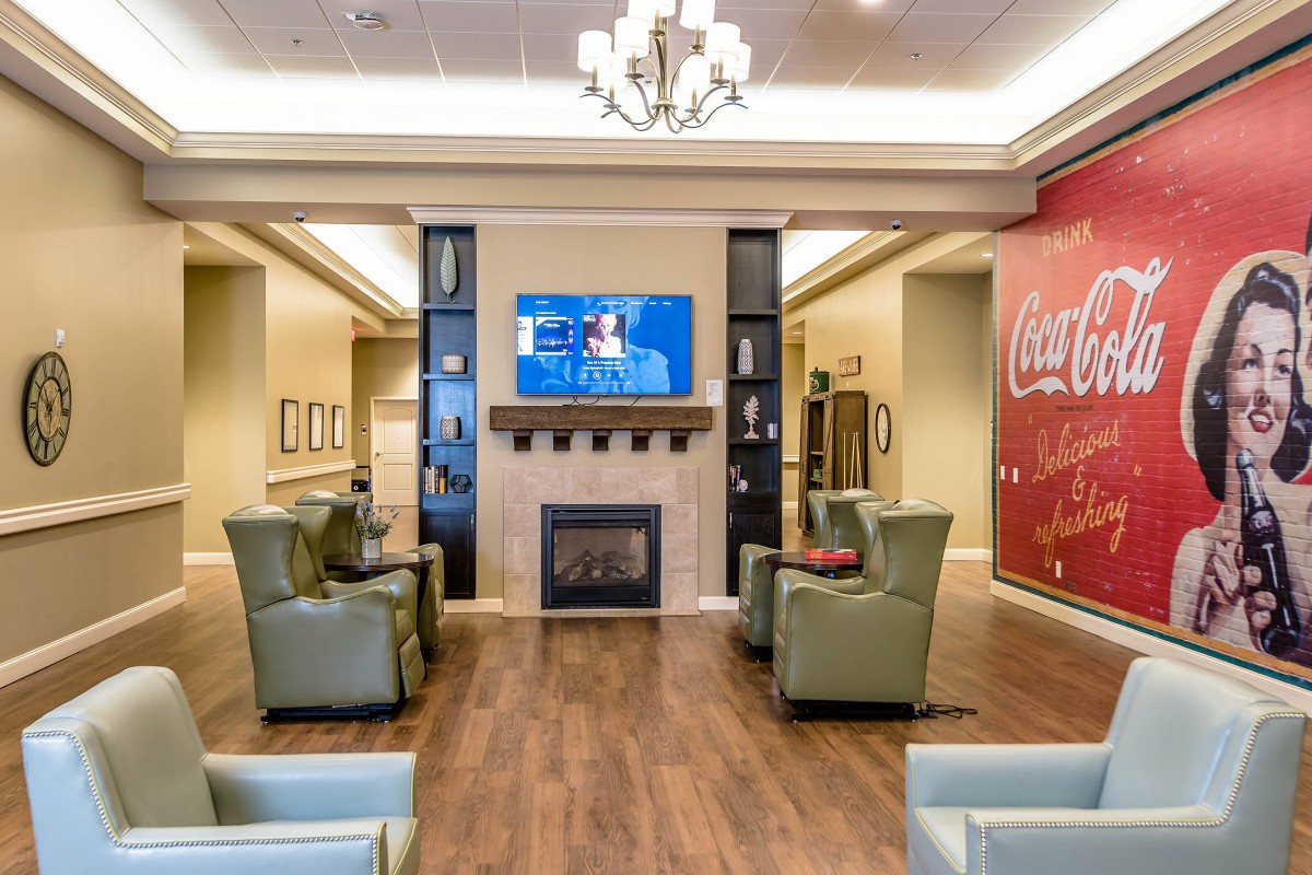 A modern lounge area featuring a fireplace and television, with comfortable seating and wood flooring.