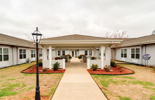 A welcoming pathway leads to the entrance of a neatly landscaped residential building.