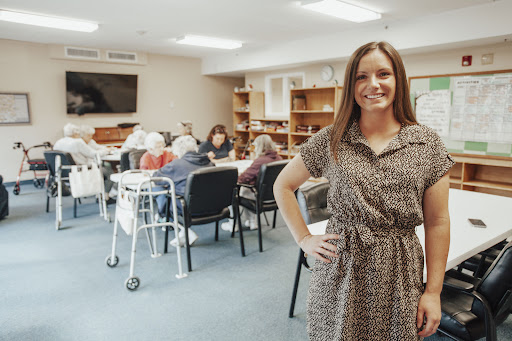 A dedicated caregiver engaging with the elderly in a warm communal environment.