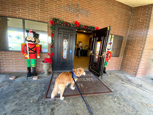 A dog stands at the entrance of a building adorned with holiday decorations and nutcracker figures.