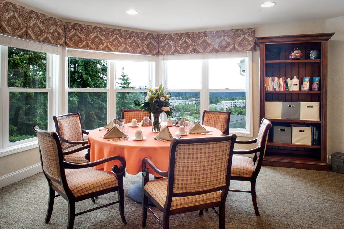 A neatly arranged dining room with a round table and chairs, overlooking a scenic window view.
