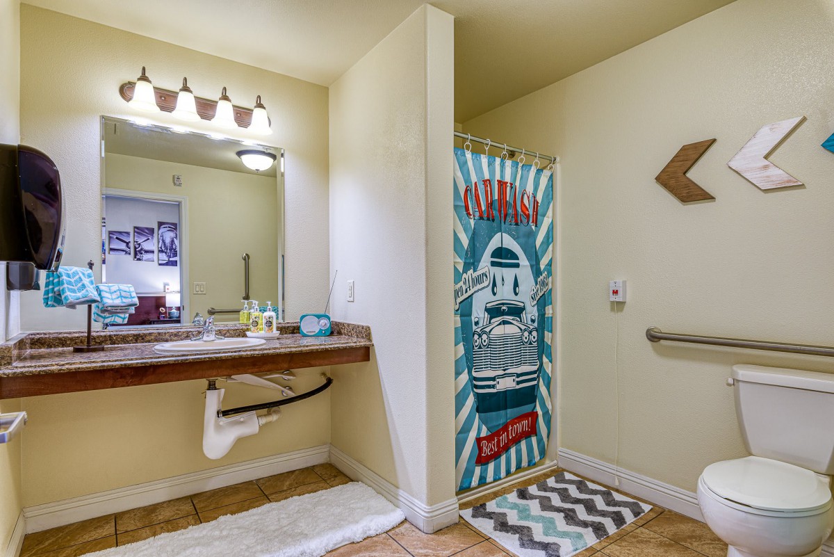 A bathroom with a decorative shower curtain and accessible features.