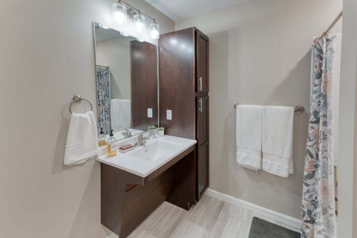 A modern bathroom with a mirror, sink, and neatly arranged towels.