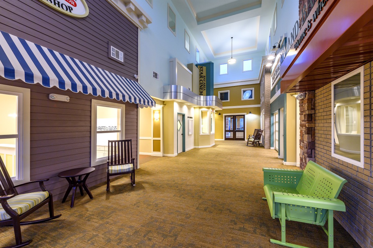 A decorative indoor corridor with colorful building facades and seating areas.