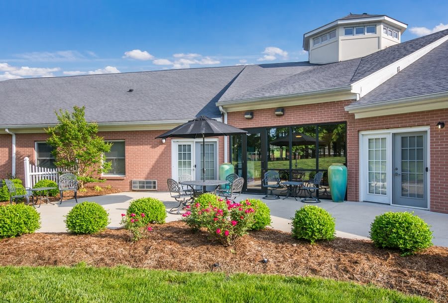 A modern house with a patio featuring outdoor furniture and well-maintained landscaping on a sunny day.