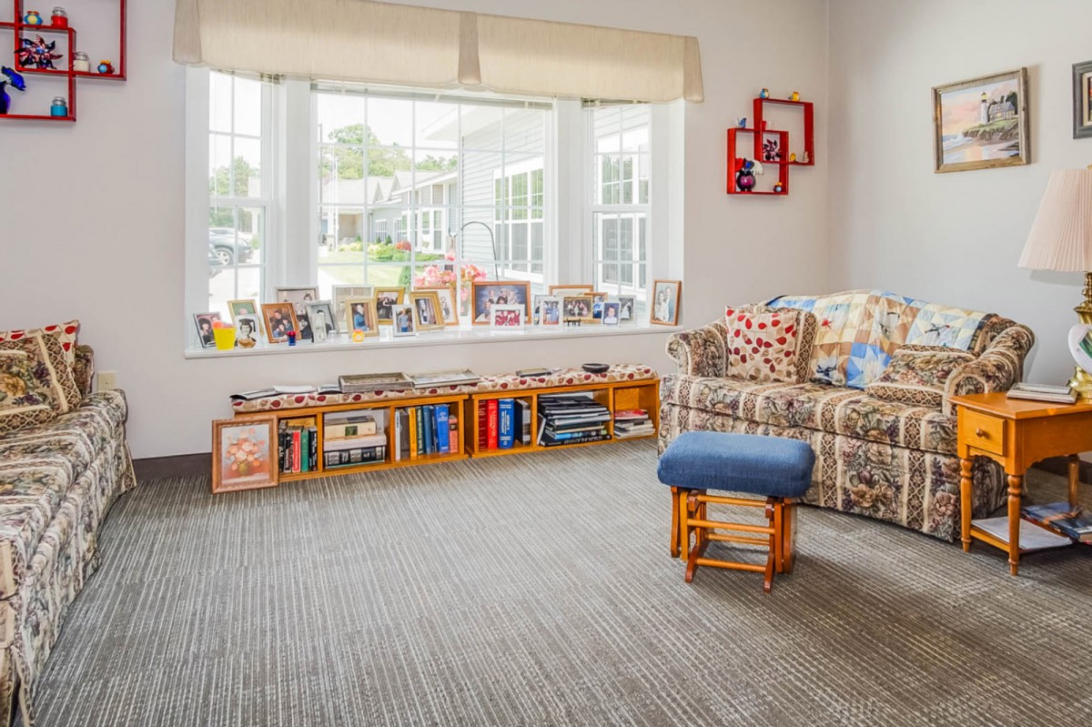 A cozy living room with a window seat and bookshelf, filled with natural light.