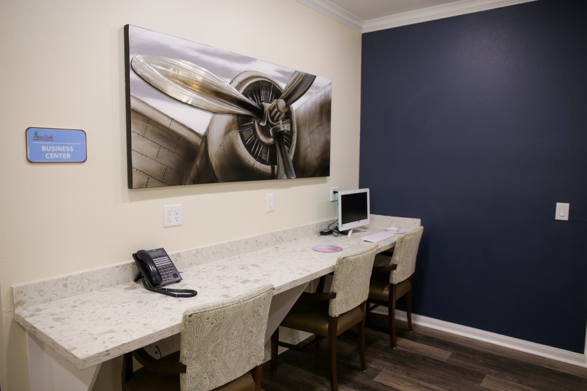 A small office space featuring a desk with chairs, a computer, and a telephone, complemented by artwork on the wall.