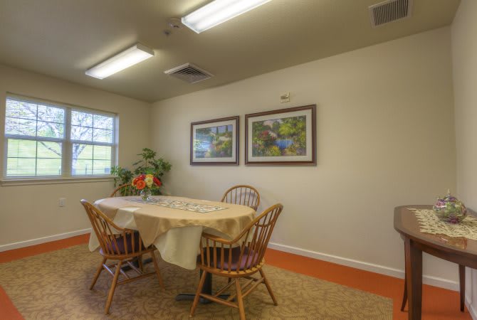 A cozy dining area with a table and four chairs, decorated with wall art and indoor plants.