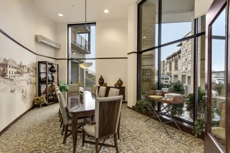 A modern and spacious dining room with large windows, wooden furniture, and decorative items.