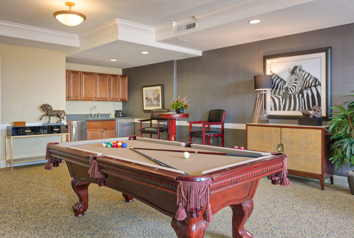 A stylish game room featuring a billiards table and a cozy bar area.