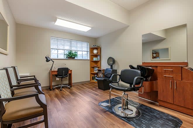 A bright and spacious hair salon interior with styling chairs, mirrors, and a work desk.