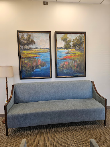 A cozy living space featuring a blue sofa and two colorful landscape paintings.