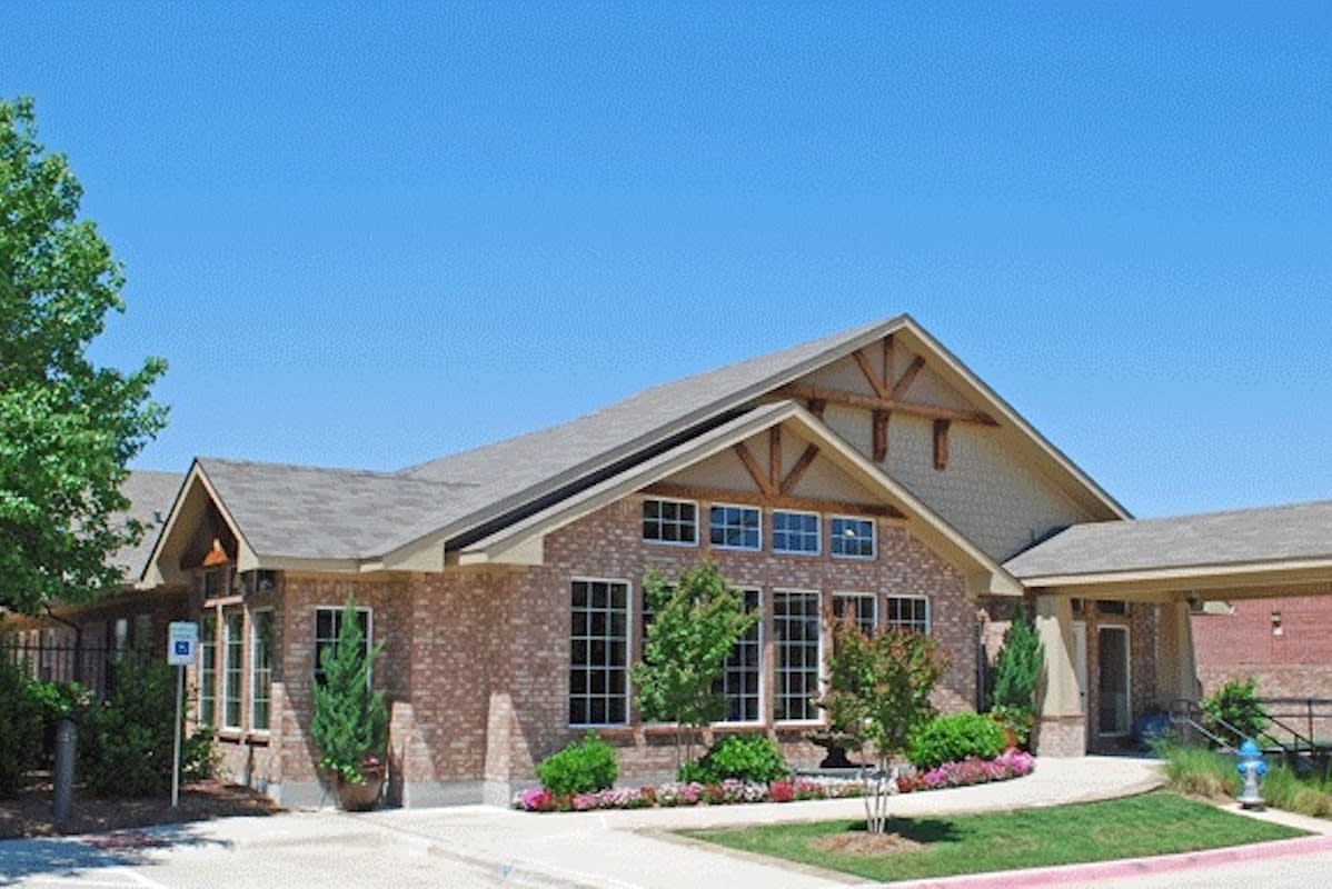 A single-story brick house with a well-maintained lawn under a clear blue sky.
