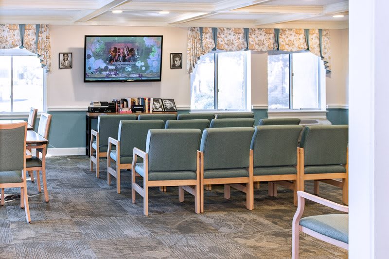 A waiting room with rows of chairs and a television mounted on the wall.