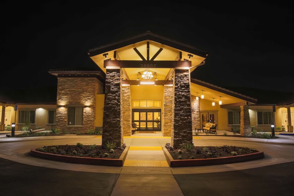 Illuminated entrance of a building with stone pillars at night.