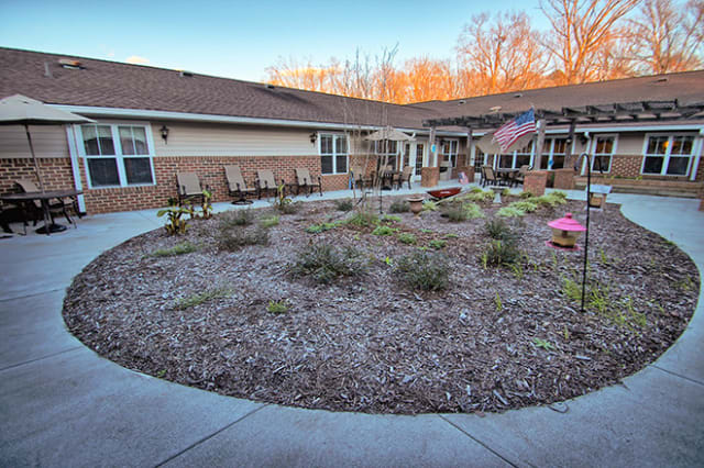 A well-maintained courtyard with a circular garden and seating area outside a building.