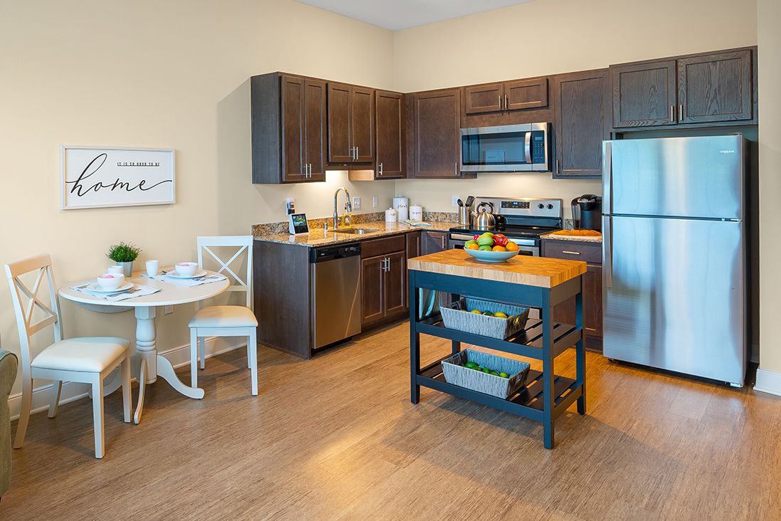 A modern kitchen with stainless steel appliances, wood cabinets, and a central kitchen island.